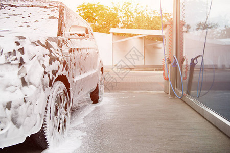 时洗车时涂上白色清洁泡沫的汽车图片