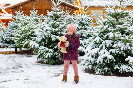 穿着冬装和玩具的快乐孩子在圣诞市场上选择圣诞树图片