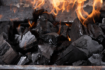 铁烤架上明亮燃烧的黑煤背景图片