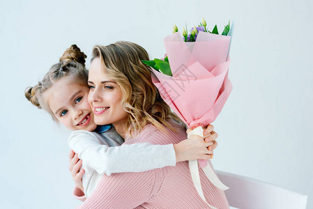 微笑女儿的肖像与花束和快乐的母亲互相拥抱图片