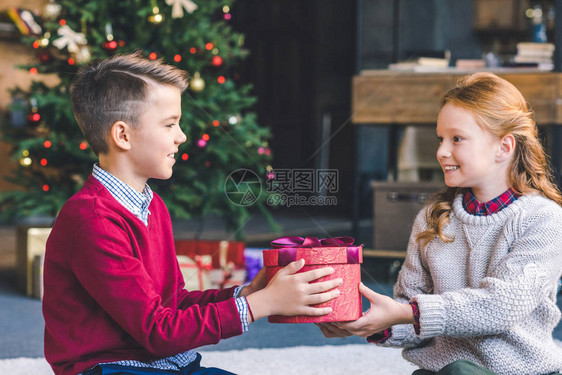 快乐的男孩给美丽的小女孩圣诞节礼图片
