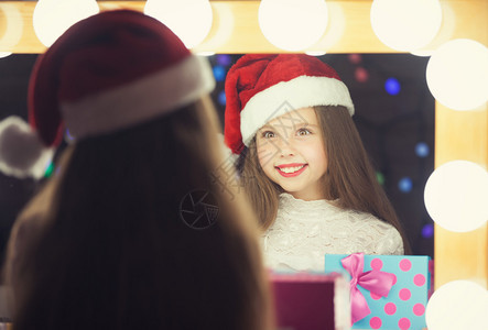 穿着红色圣诞老人帽子的年轻女孩拿着礼物盒图片
