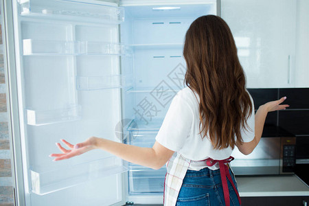 隔离期间厨房里的年轻女子看上面没有的空冰箱架子饿了不会做饭女人的背影不图片