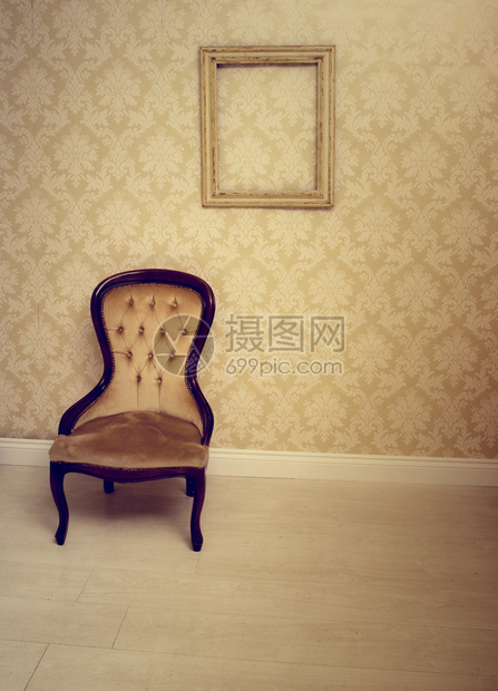 贴着墙纸的房间里的古董软垫椅子图片