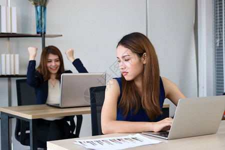 愤怒的亚洲商业妇女期待成功的竞争对手同事在办公室图片