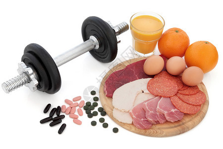 健身哑铃重量与补充片剂鸡肉牛排培根鸡蛋橙子和一杯冰沙汁的高蛋白食图片