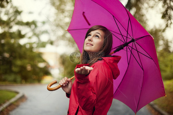 粉红色雨伞下的年轻女子图片