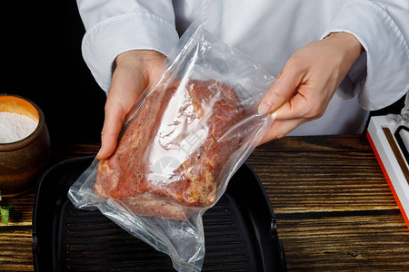 厨师把肉包在真空袋里图片