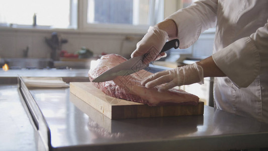 屠夫在商业厨房烹饪和上菜概念中的木板上切割大片新鲜图片