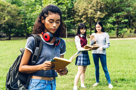 微笑的女国际学生或青少年站着拿书图片