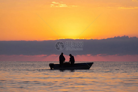 两名渔民在海上乘船捕鱼背图片