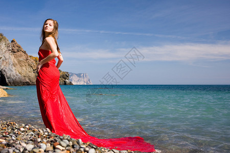 海边沙滩上穿红裙子的美女背景图片