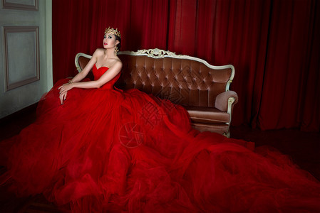 穿着红色长裙和皇家冠的漂亮女孩在摄影棚里坐在古托沙图片