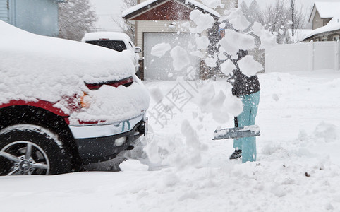 雪中西装的女人在暴风雪过后铲图片