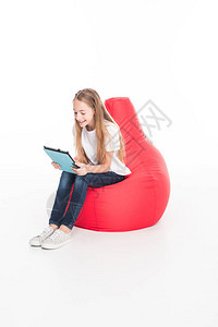 可爱的女青年使用数字平板电脑坐在红豆袋椅上图片