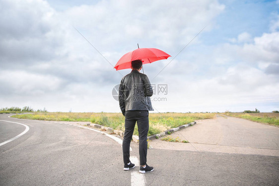 在十字路口站着有伞的青年男子图片