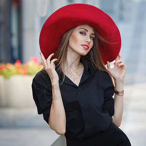 美丽的年轻时髦女人穿着黑礼服和红帽子穿著V图片