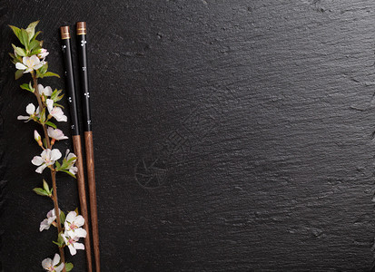 黑石背景的日本寿司筷和樱花带有复制空图片