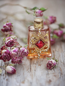 旧木背景上的干茶玫瑰和复古香水瓶图片