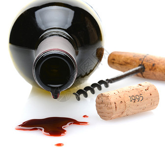 一个红葡萄酒瓶的特写镜头与滴水和酒溢出在前景图片