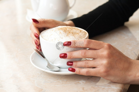 上午一杯卡布奇诺咖啡和一只红钉子和图片