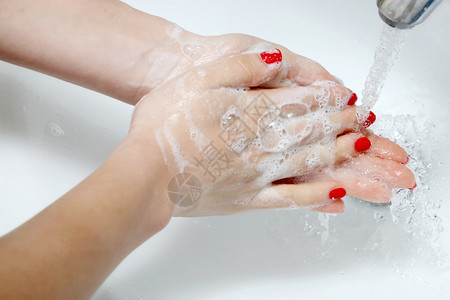 用肥皂泡在浴室水槽上的手特写图片