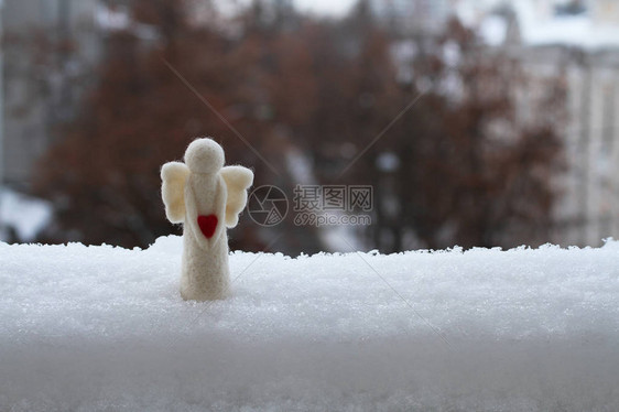 一个羊毛玩具天使站在雪地上站在阳台对街的栏图片