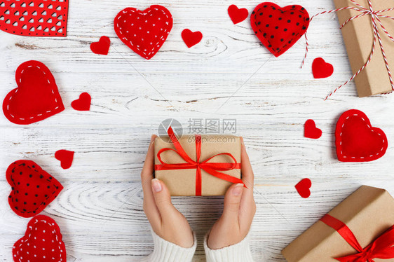 女孩的手给情人节礼物盒里面有红心在白色的老木图片