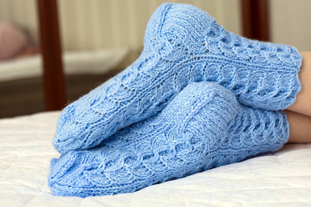 穿着蓝羊毛袜的床毯下女双腿寒冷天气图片