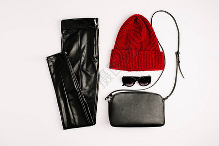白色背景上的女时尚服装和配饰红色帽子黑色钱包太阳镜和紧身裤平躺图片