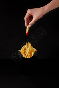 黑纸上隔着一盒薯条被倒在番茄酱里的女人图片