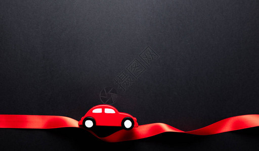 穿着红色丝带的可爱玩具车在黑暗灰色背景图片