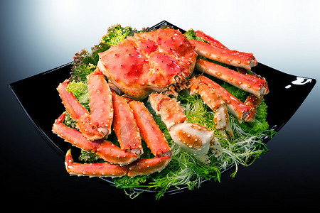 红帝王蟹肉放在黑盘上配上酸橙和沙拉叶图片