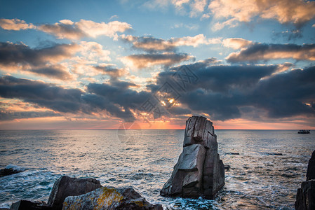 日出在岩石沙滩上多彩的云图片