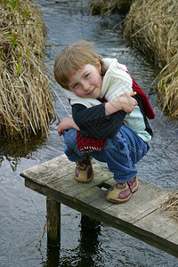 小女孩坐在河边的桥上图片