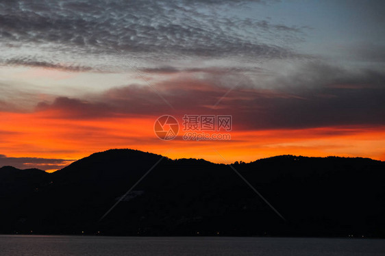 橙色落日天空下的黑色山丘剪影图片