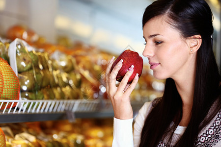 年轻女在超市闻到鲜苹果的画面她手图片