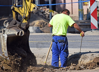 人正在一个挖土机旁边的公路建图片