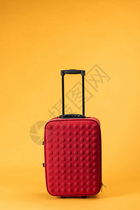 黄色背景带轮子的红色旅行包背景图片
