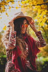 身戴帽子太阳眼镜红色围巾和外套露天公园户外秋季时装肖图片