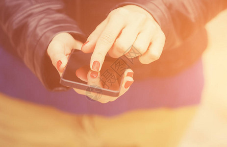 女手用红色指甲擦黑智能手机的图片