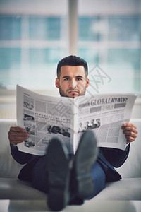 一位坐在沙发和阅读报纸图片