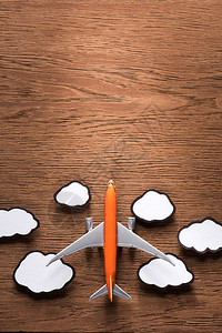 玩具飞机和木质表面纸云的顶部视图片