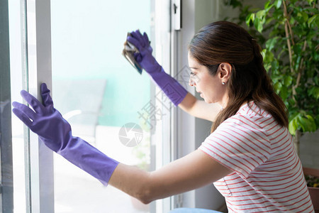 妇女佩戴橡胶手套用纸张擦扫家门和窗户的图片