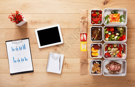 健康餐厅商务午餐和饮食计划新鲜的每日膳食交付箔盒咖啡和平板电脑中的健身营养蔬菜肉类和水果顶视图图片