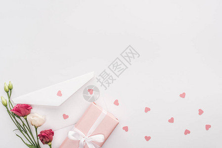 在白色上隔离的礼品盒鲜花信封和纸心的顶部视图图片