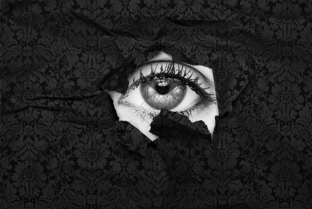女眼睛从黑色壁纸的一个洞里窥视图片
