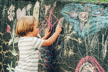 可爱的小男孩用粉笔在户外画为儿童图片