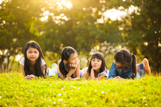 小亚洲女孩躺在阳光下的绿草图片