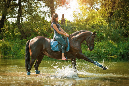 在炎热的夏日骑马的女人沿着河边骑行图片